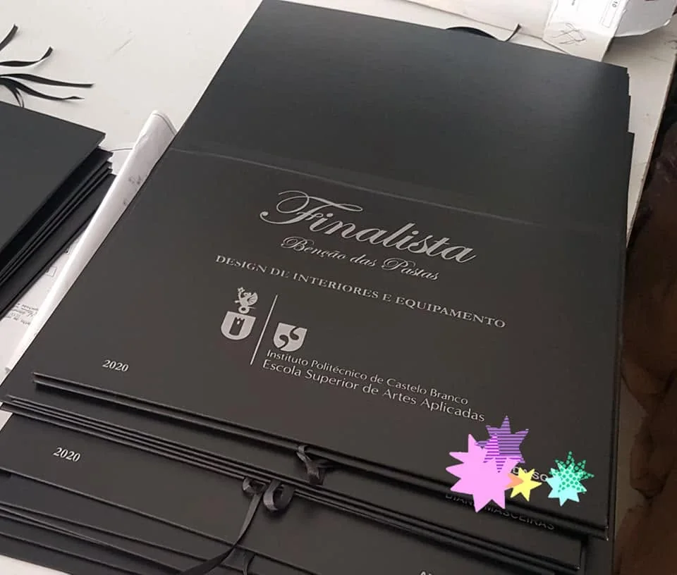 Pastas com personalização e fitas para assinalar a conclusão do percurso académico.