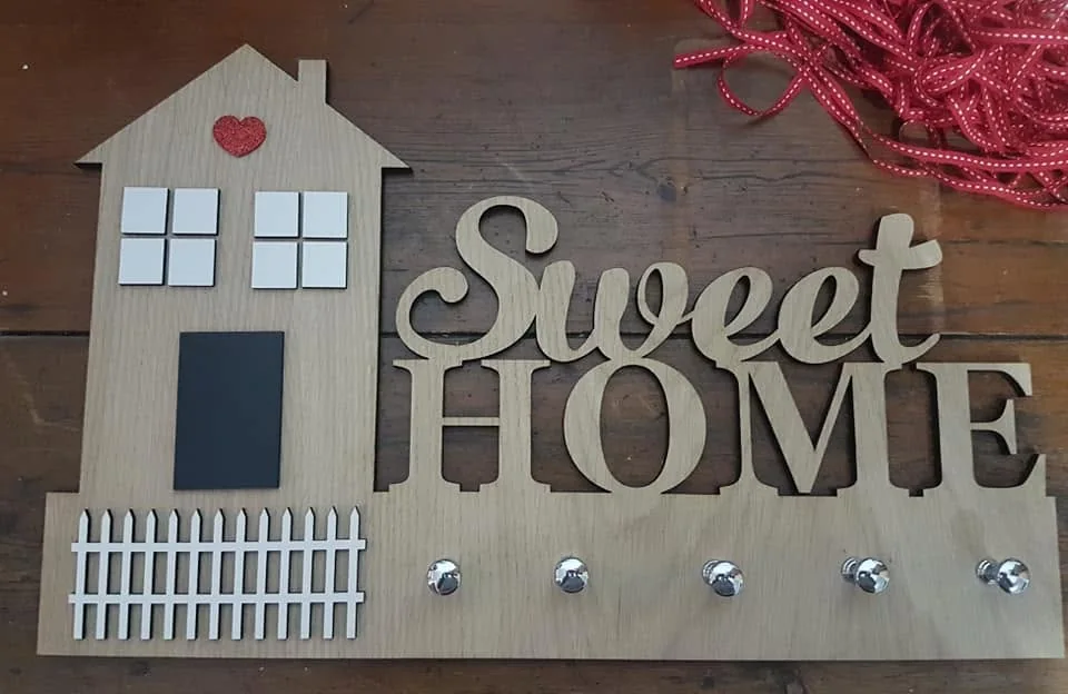 Suporte de parede com ganchos e elementos personalizados para organizar chaves.