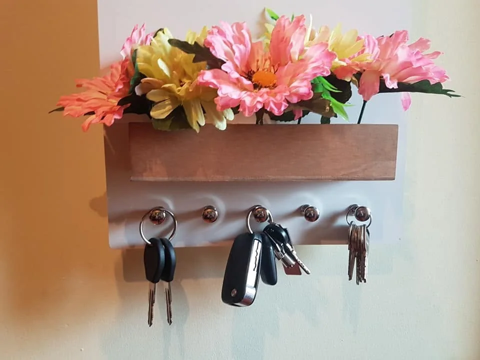 Suporte de parede com ganchos e elementos personalizados para organizar chaves.